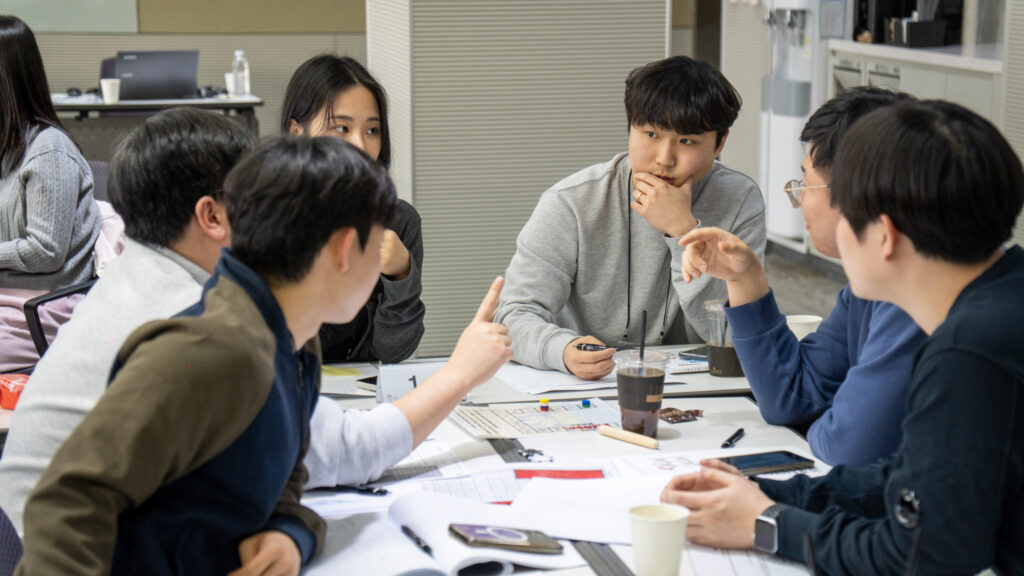 다른 팀의 정보를 캐내기 위해 협상가 역할을 맡은 참가자들이 모여 정보를 교환하고 베팅 작전을 세우는 보드게임 팀빌딩 현장