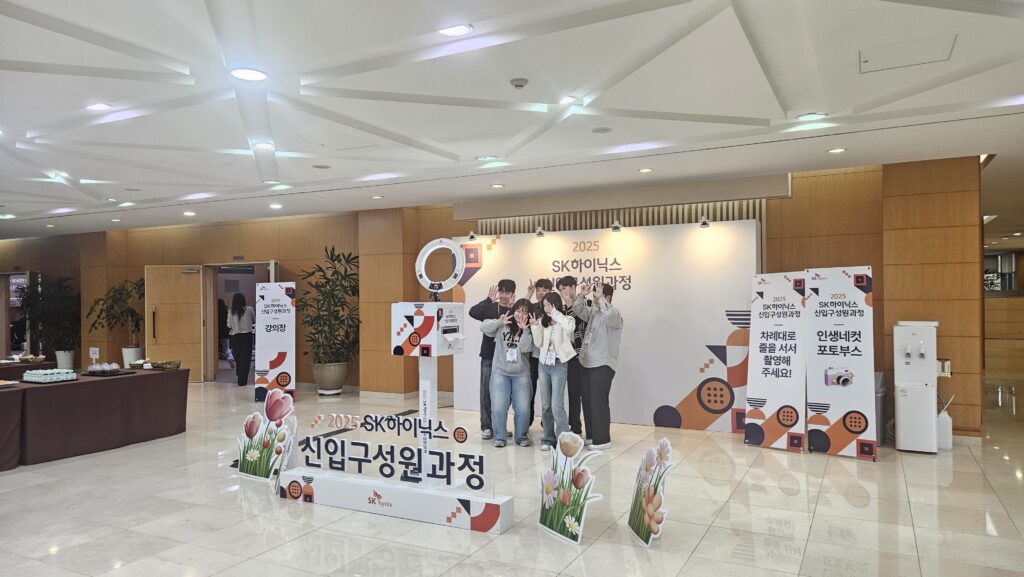 SK하이닉스 신입구성원 과정 교육장 외부에 마련된 인생네컷 포토부스에서 다 함께 브이 포즈로 기념 사진을 촬영하며 친목을 도모하는 사원들
